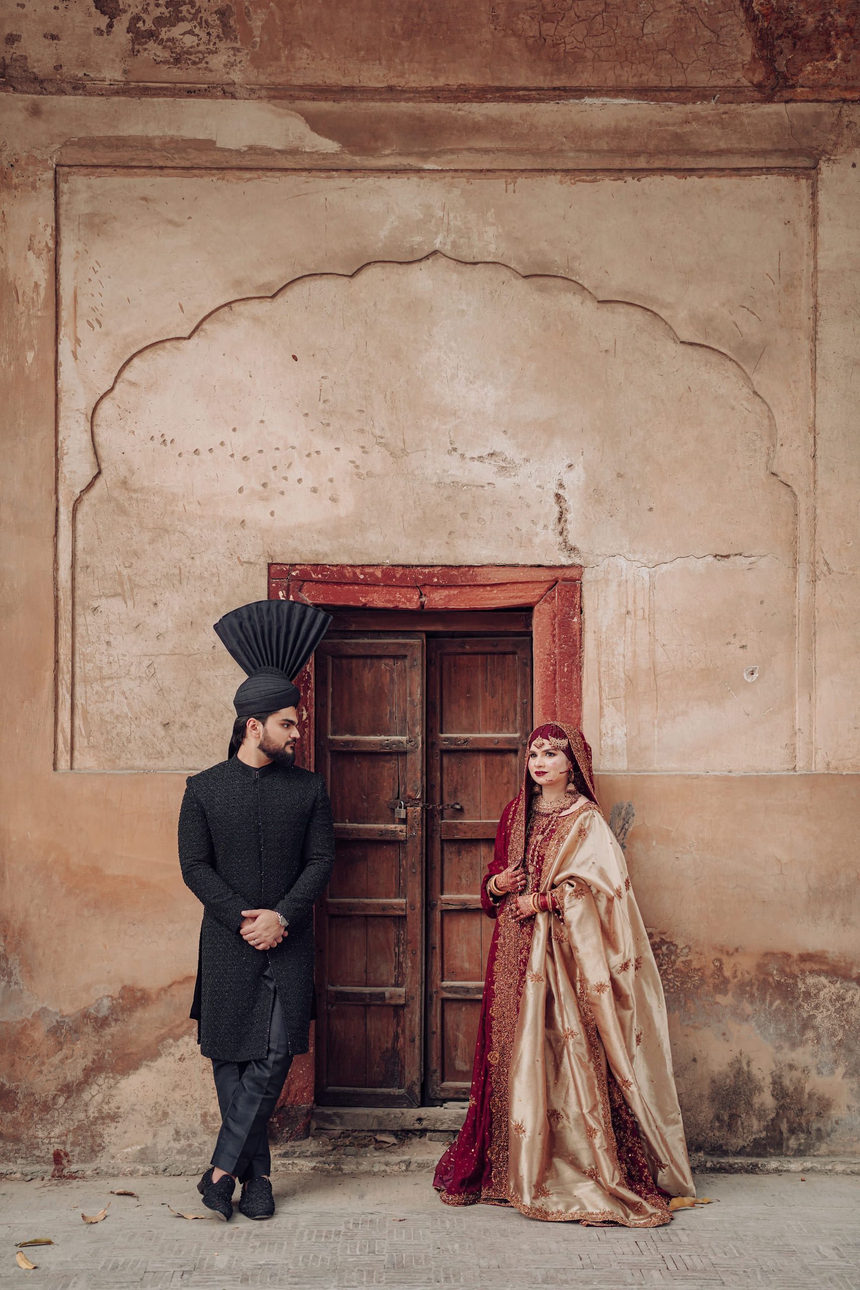 Bride and groom beside an ornate weathered Mughal doorway, Lahore wedding photography